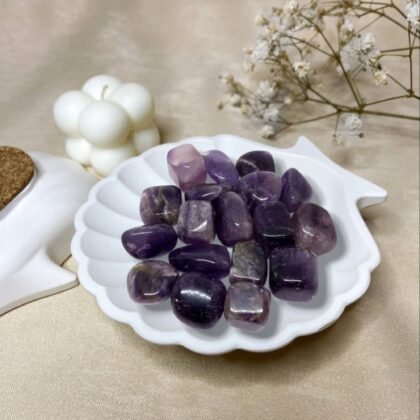 A collection of polished Amethyst crystal tumbles featuring vibrant violet and deep purple translucent colors.
