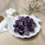 A collection of polished Amethyst crystal tumbles featuring vibrant violet and deep purple translucent colors.