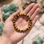 A high-quality Tiger Eye crystal bead bracelet showing vibrant golden-yellow chatoyant bands on a white background.