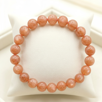 A premium Sunstone crystal bead bracelet showing warm peachy-orange colors with natural internal metallic sparkles.