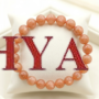 A premium Sunstone crystal bead bracelet showing warm peachy-orange colors with natural internal metallic sparkles.