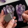 A hand-carved natural Amethyst crystal angel featuring deep purple hues and translucent polished finish.
