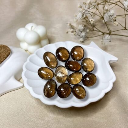 A collection of polished Smoky Quartz crystal tumbles featuring translucent brownish-grey tones and natural clarity from lakshya gems mumbai