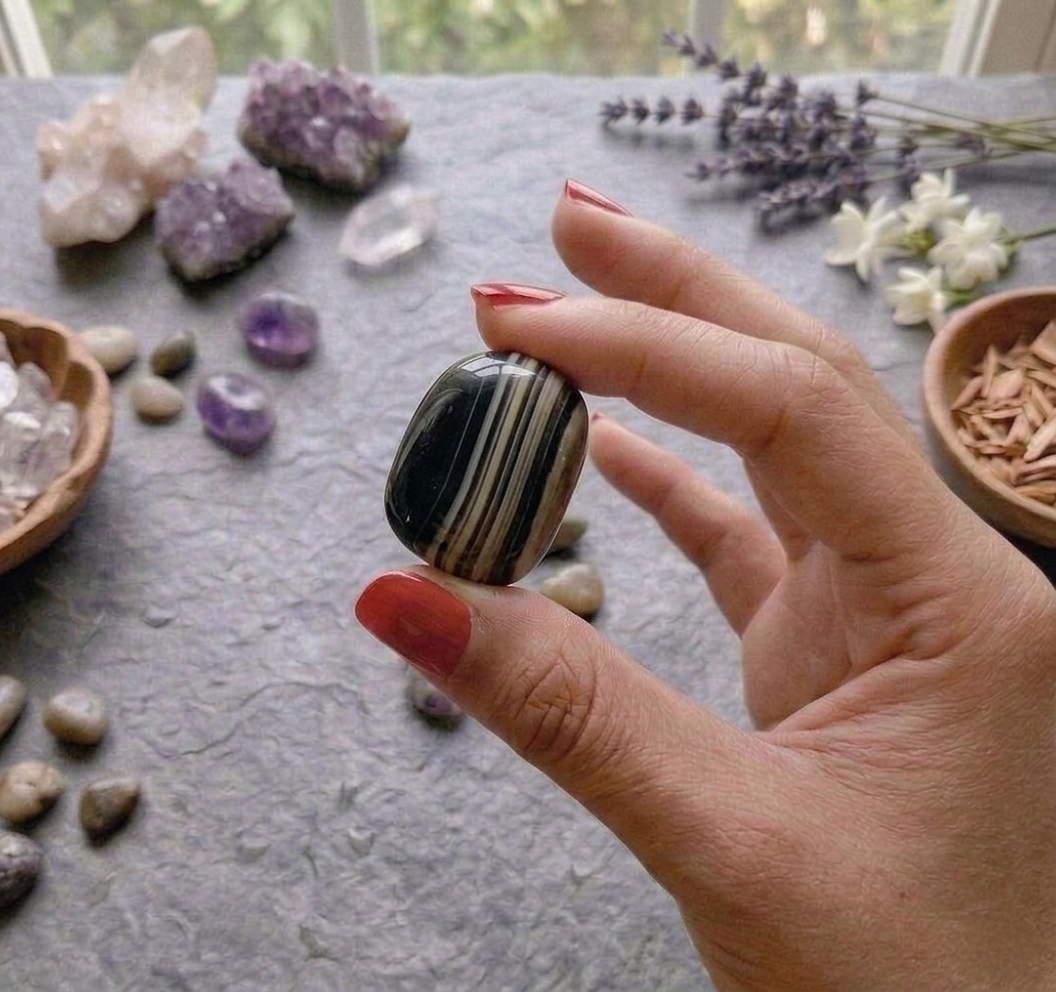 A collection of polished Sulaimani Agate crystal tumbles showing natural bands of black, white, and translucent grey.