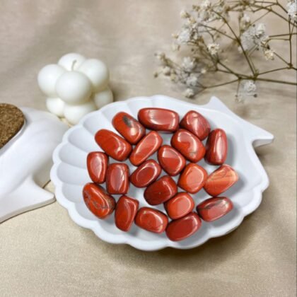 A collection of polished Red Jasper crystal tumbles showing a deep, opaque brick-red color and smooth surface.
